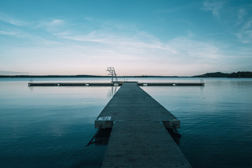 Fototapeta na wymiar Perspective view at the old wooden pier in a calm lake at the sunset.