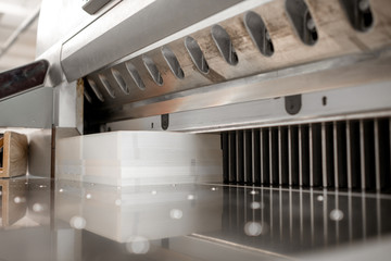 Cutting a stack of paper with professional press machine at the manufacturing