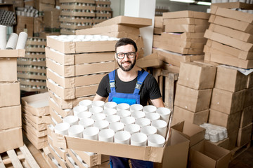 Portrait of a handsome worker in unifrom standing with paper tubes at the old printing manufacturing