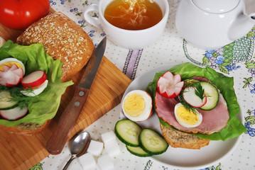 sandwich with lettuce ham with fried egg and dill radish and parsley with hot tea for a healthy breakfast
