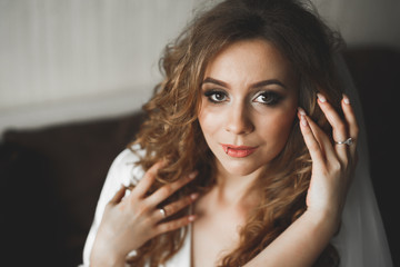 Luxury bride in white dress posing while preparing for the wedding ceremony