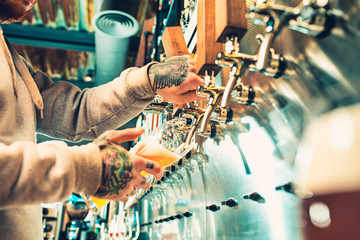 Hand of bartender pouring a large lager beer in tap.