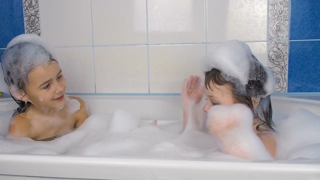 Children take a bath. Little girls are playing in the bathroom.