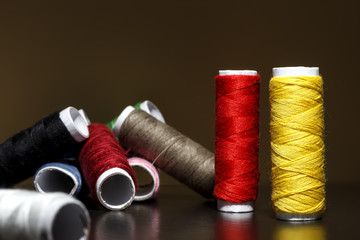 Background with a lot of colorful coils with threads. Bobbins are stacked in three rows, one on the other. The winding is erratic. Multicolored threads.