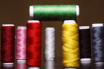 Background with a lot of colorful coils with threads. Bobbins are stacked in three rows, one on the other. The winding is erratic. Multicolored threads.