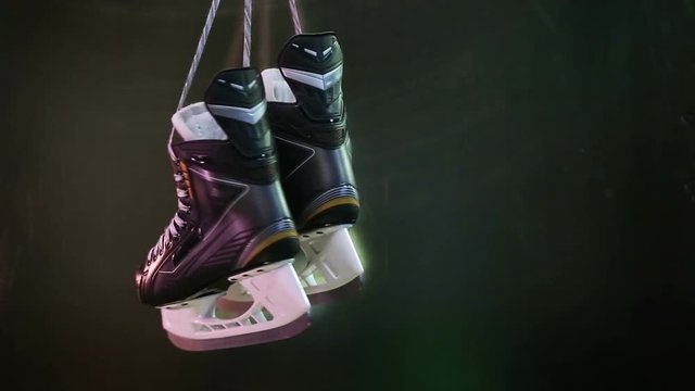 Ice hockey skates hanging on grey background.
