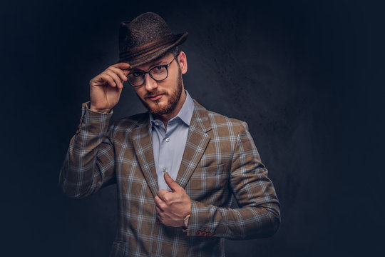 Studio portrait of a bearded hipster in hat and glasses wearing 