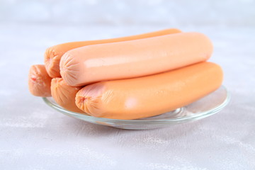 Raw sausages on a wooden board on a gray concrete table.