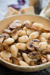 Close-up of italian potato gnocchi served with fried champignons, selective focus, vertical shot