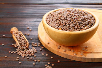Red lentils in a wooden bowl on a wooden table.