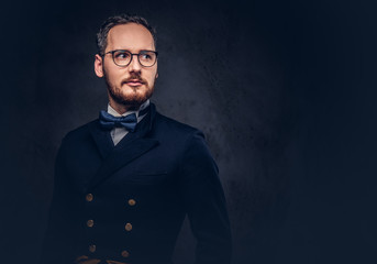 Fototapeta premium Portrait of a bearded male in glasses and antique suit on a dark