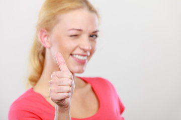 Winking blonde woman showing thumb up