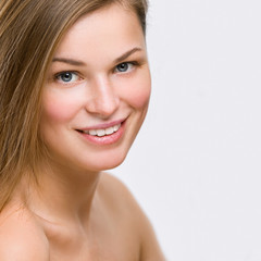 Fototapeta premium Portrait of a beautiful young smiling woman on a gray background