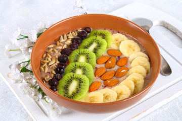 Breakfast berry smoothie bowl topped with bananas, berries, kiwi, almonds and sunflower seeds.
