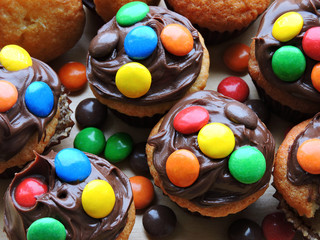 Mini muffins with topping from chocolate cream and colored sweets.
