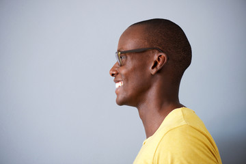 Profile portrait of black man smiling with glasses against gray background