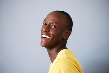 Side of handsome black man laughing against gray walll