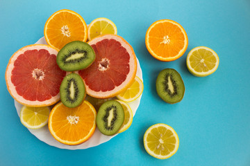 Sliced tropical fruits on the white plate on the blue  background.Top view.
