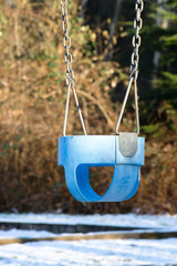 Empty baby swing at snowy playground