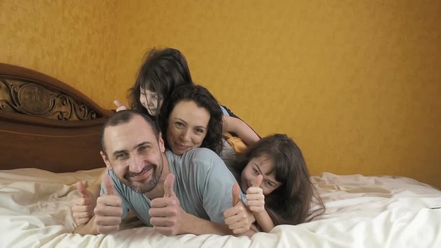 Happy family on the bed. Merry family show thumb.