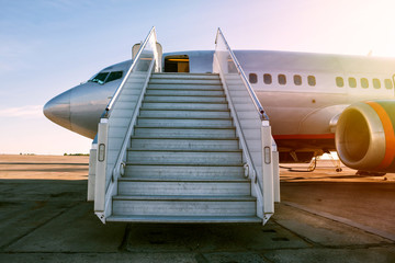 Fototapeta premium Pasażerski samolot z abordażu krokami w ranku słońcu