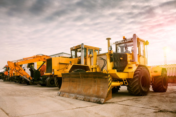 Obraz premium Two heavy wheeled tractor one excavator and other construction machinery in the morning sun