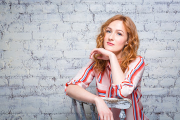 portrait Beautiful young woman student with red curly hair and freckles on her face sitting on a...