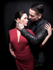 Attractive couple of professional dancers dancing passionate tango on dark background