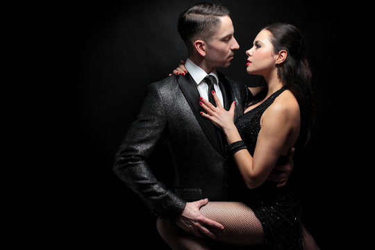Attractive couple of professional dancers dancing passionate tango on dark background