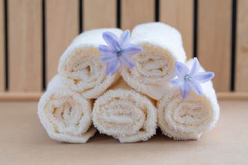 Fototapeta na wymiar Beige bath towels on wooden background and a fresh violet hyacinth flowers. Spa concept.