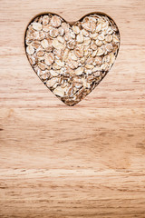 Oat cereal heart shaped on wooden surface.