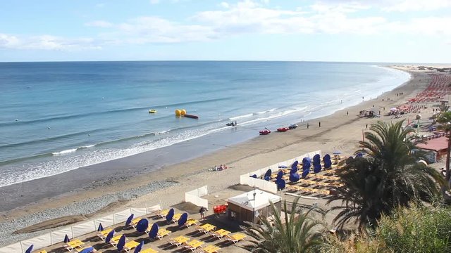 Pan view of Playa del Ingles with Maspalomas iconic sand dunes on the background in Gran Canaria island, Spain. Sunny winter day on the beach in Canary Islands. Travel destination, vacation concept
