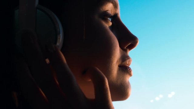 Girl in headphones. Beautiful girl in headphones in front of a window in the rays of sunlight.