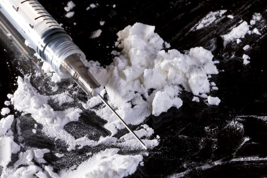 White powder (cocaine) and syringe on glass table