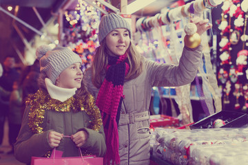 Smiling girl with woman are buying toys for X-mas tree