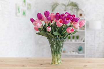 Tulips in a vase on a wooden table. Scandinavian interior.