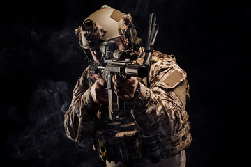 soldier or private military contractor holding rifle. Image on a black background. war, army,...