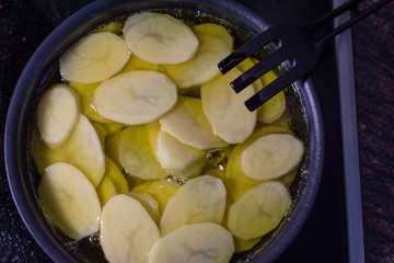 Cut potatoes in the pan with oil, making spanish omelette