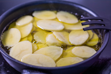 Cut potatoes in the pan with oil, making spanish omelette