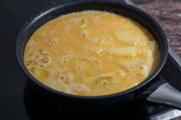 blended eggs and cut potatoes, making spanish omelette, Spanish tortilla, an omelette tortilla de patata, a typical Spanish dish of eggs, potatos, onions and olive oil.