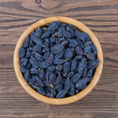 Raisins in a wooden bowl on a wooden background. Top view.