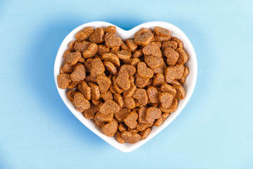 Dry cat food in the form of hearts lies in the saucer in the form of heart