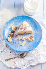 A piece of banana cake with nuts, sesame and cranberry on a wooden table