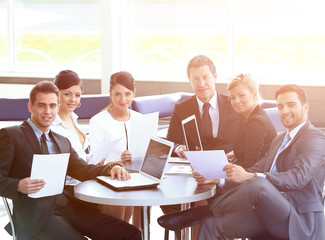 group of business people with documents sitting at a table in th
