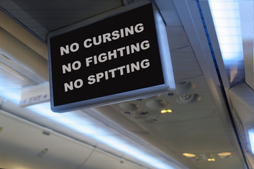 Humorous interior plane TV monitor message prohibiting passengers from rude and unruly behavior. 