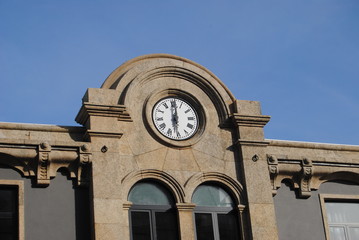 São 18 horas, relógio no topo de um edifício construído em pedra