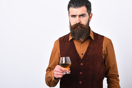 Barman in elegant uniform with serious face serves cognac.