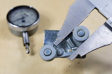 Tools and measuring accessories on a wooden workshop table. Making control measurements using calipers, micrometers and other measuring tools.
