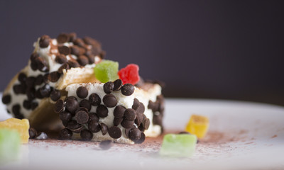 Speciality Italian ice cream with flakes of dark chocolate, colorfull dried fruit, violet background