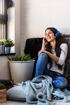 Beautiful young woman at home enjoys listening music